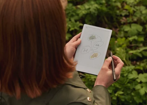 A woman in a natural environment, sketching on a reMarkable Paper Pro Move