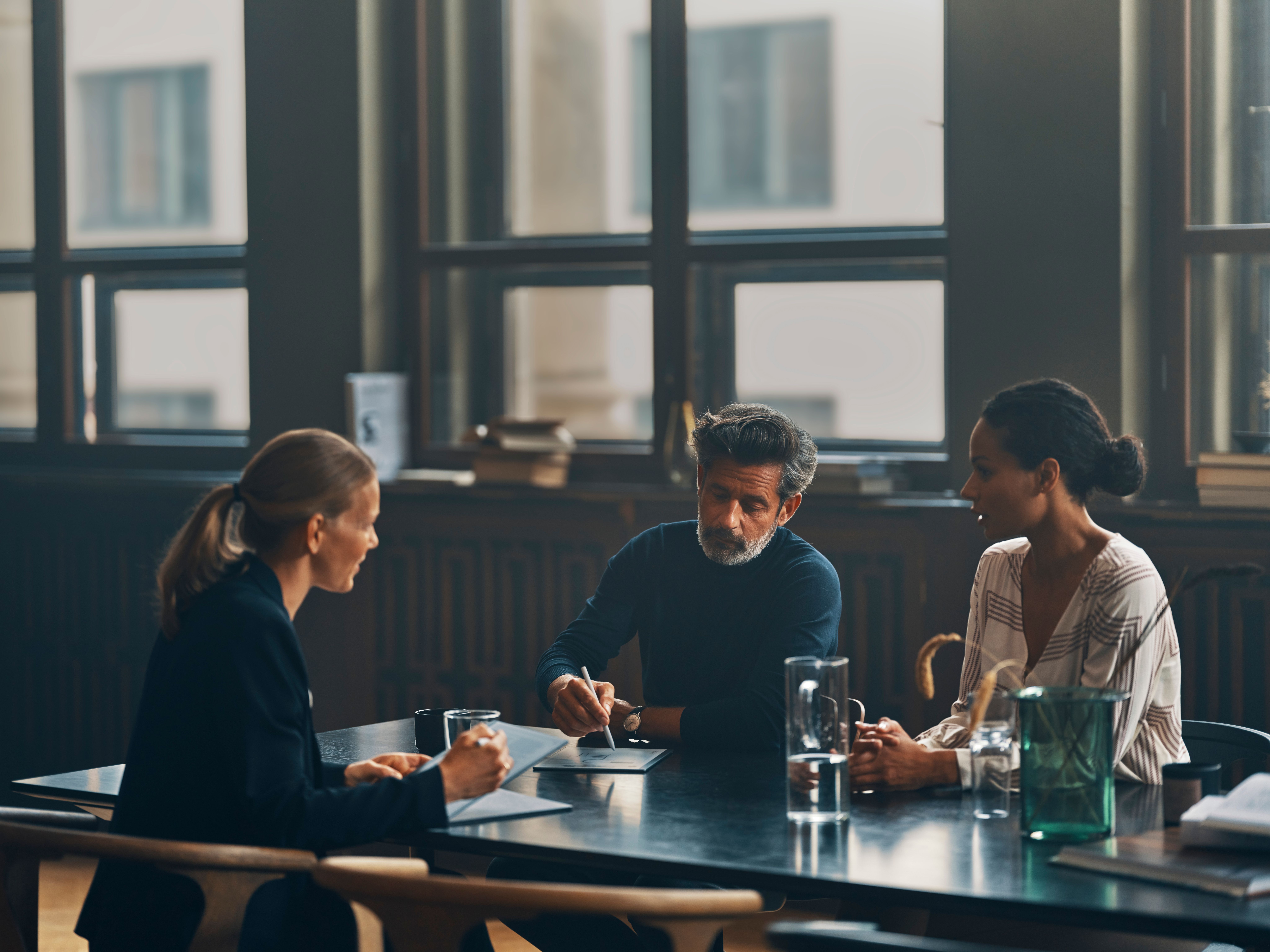 One man and two women seated around a table in an office working on their reMarkable paper tablets.