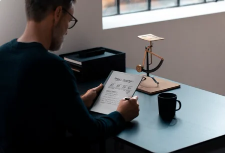 A reMarkable paper tablet showing project milestones with the Marker in hand on a desk.