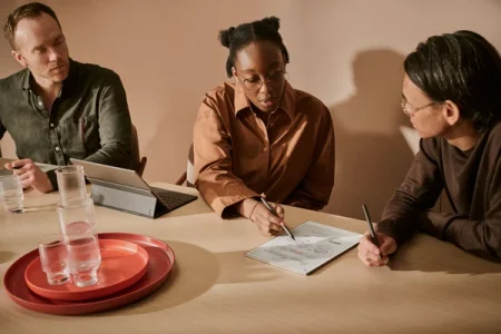 A group of people in a meeting room. One of the meeting participants are pointing towards a reMarkable paper tablet