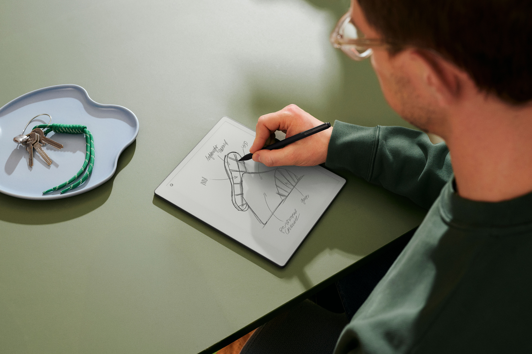 A person sitting with remarkable in his hands writing with a pen.