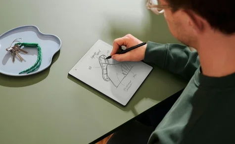 A person sitting with remarkable in his hands writing with a pen.