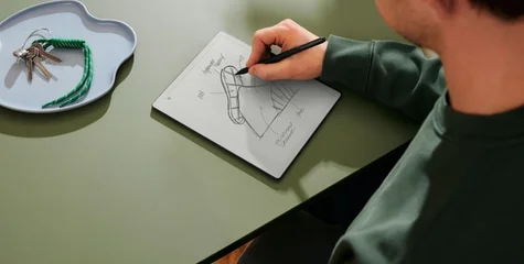 A person sitting with remarkable in his hands writing with a pen.