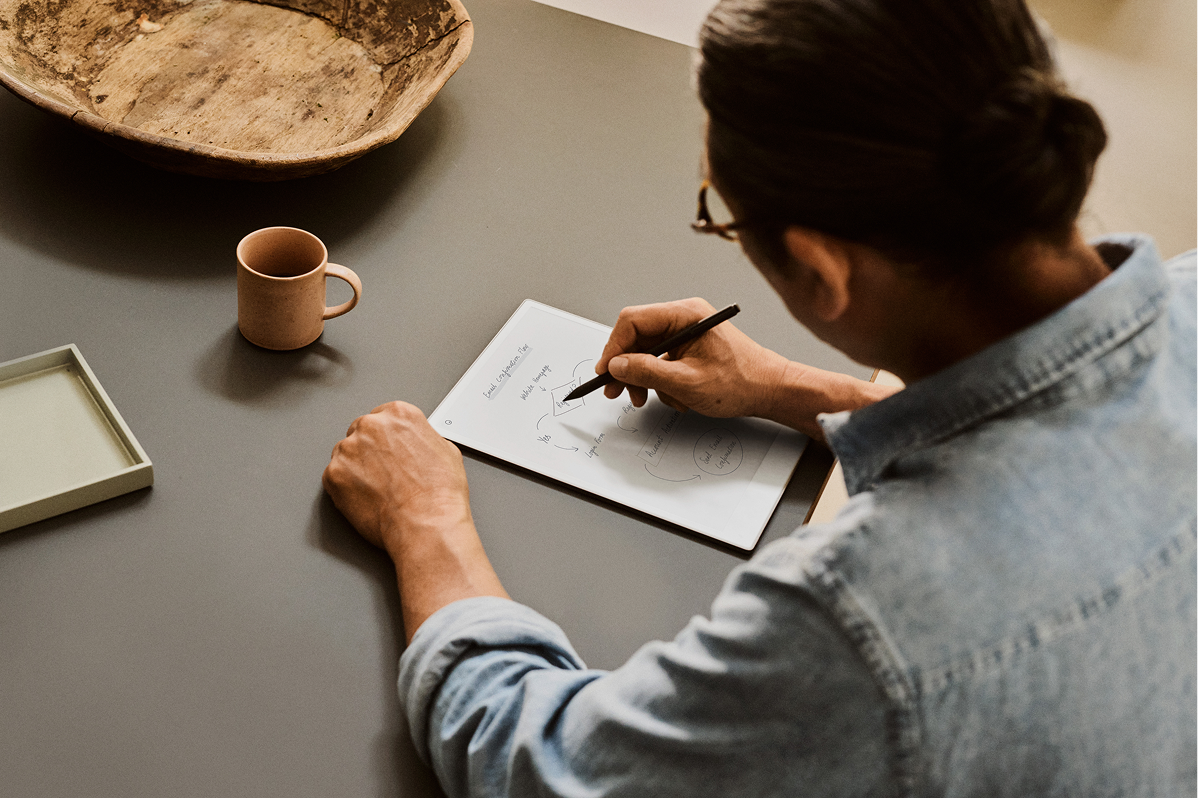 A reMarkable paper tablet with notes as a person sketches with the Marker.