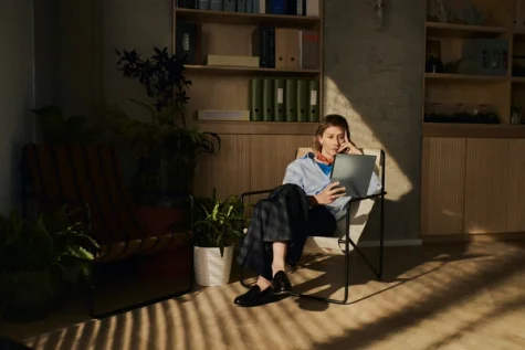 A woman using a reMarkable paper tablet while sitting in a chair.