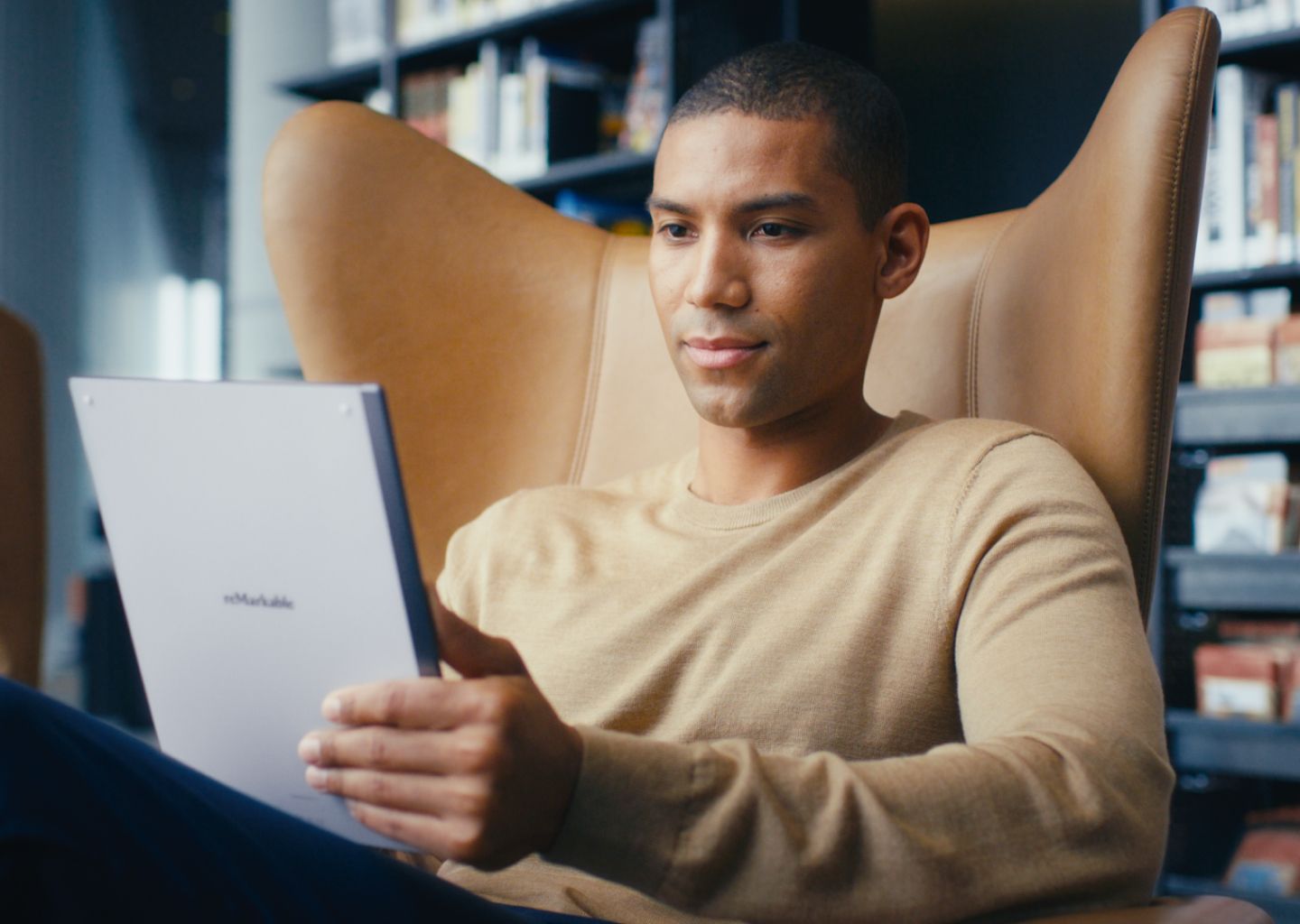 Man in a chair holding a reMarkable tablet