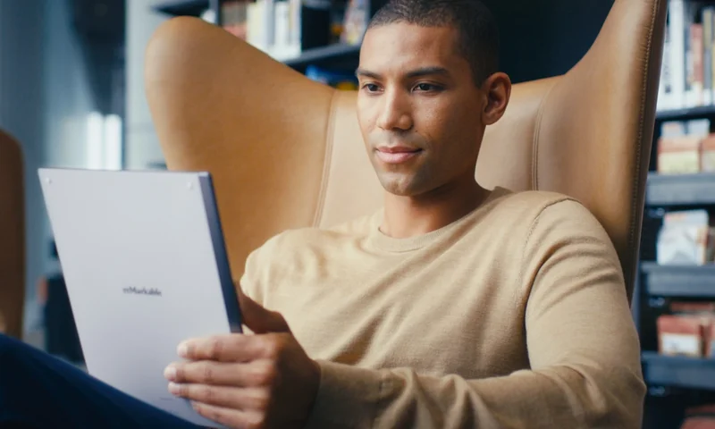 Man in a chair holding a reMarkable tablet