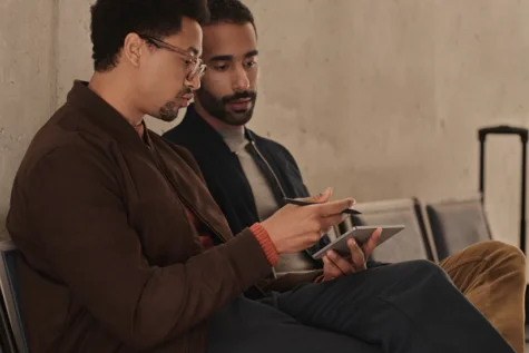 Two men sat at a bench in discussion over a reMarkable Paper Pro Move held in a landscape orientation.