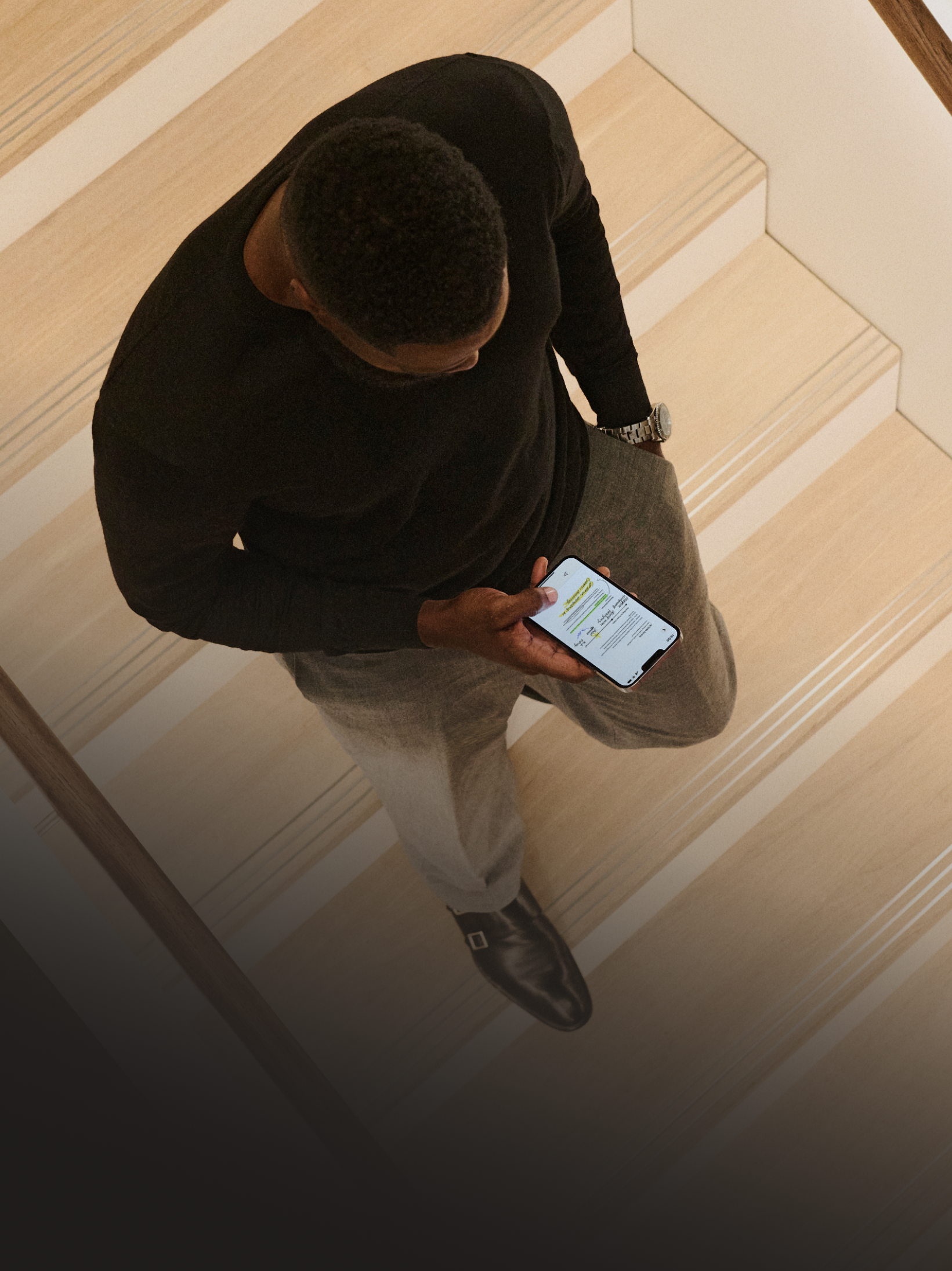 A person going down a staircase with a phone in their hands.