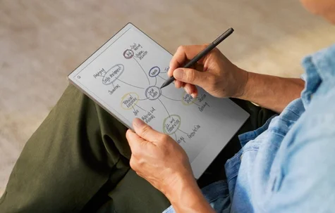 A man sitting at a table writing on a reMarkable paper tablet.