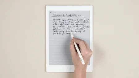 A hand writing notes on the reMarkable paper tablet before converting to text.