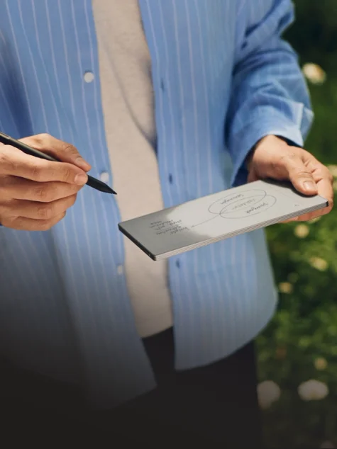 reMarkable paper tablet with the Marker. A standing person is drawing a diagram on a handheld reMarkable Paper Pro Move tablet.