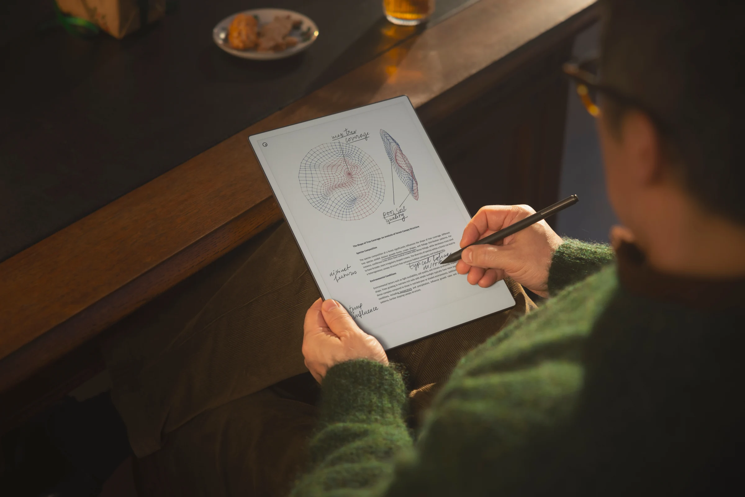 Over-the-shoulder view of a person using a marker plus to write handwritten notes and sketch diagrams on reMarkable Paper Pro.