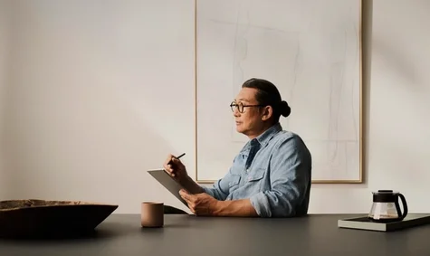 A man sitting by a table holding a reMarkable Paper Pro tablet while doing some focus work.