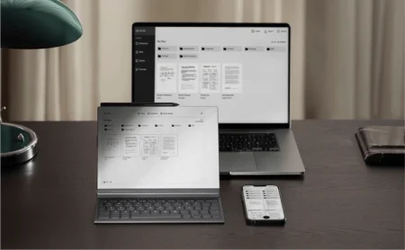 A reMarkable paper tablet, smartphone, and laptop display files on a desk, next to a lamp.