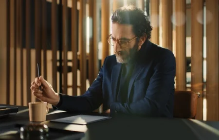 A man wearing glasses looks at a document next to a reMarkable paper tablet.