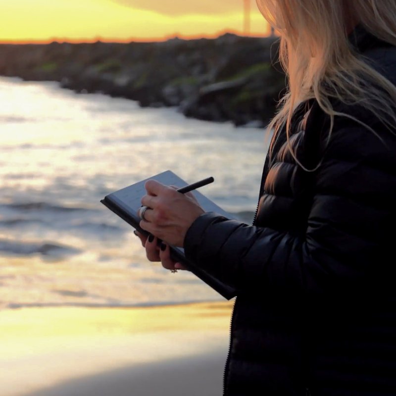 iJustine on a beach writing on a reMarkable paper tablet
