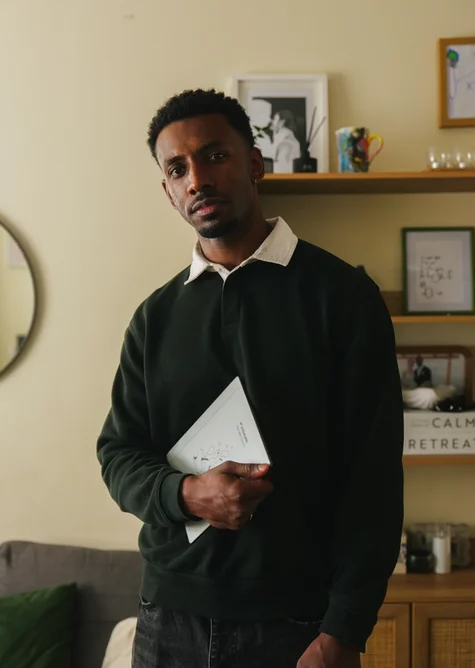Jordan Jaiyeola standing in his living room holding a reMarkable Paper Pure tablet.