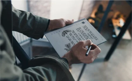 A reMarkable paper tablet displaying notes and sketches, with a person writing with the Marker.