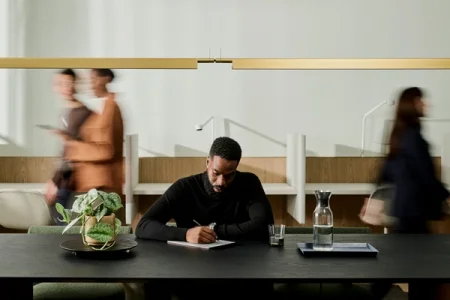 A person writing on a reMarkable paper tablet at a table.