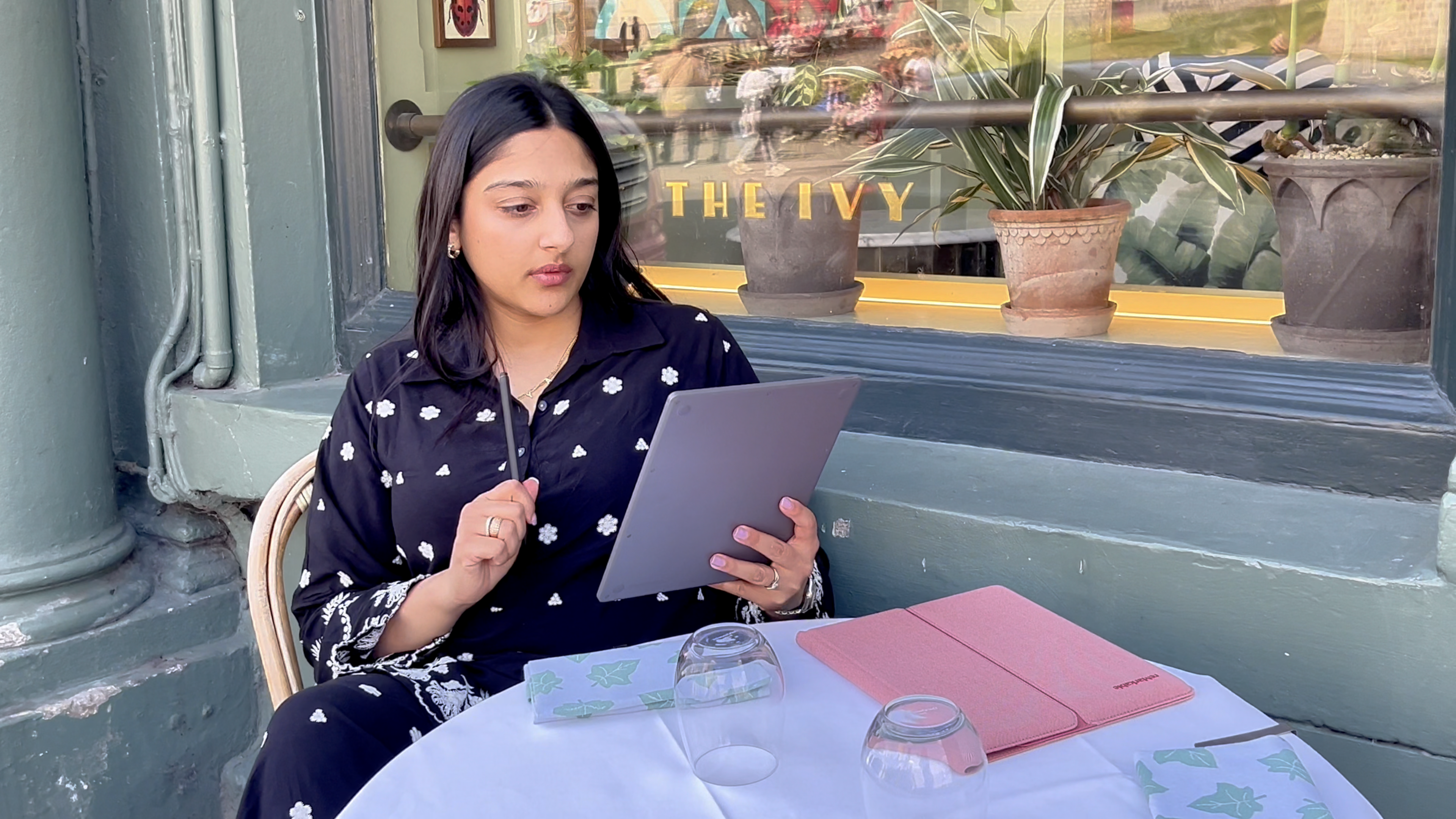 Sonya Barlow sitting outside of a café reading on her reMarkable Paper Pure tablet.