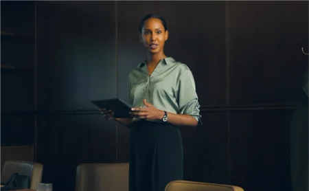 A person holding a tablet in an office setting.