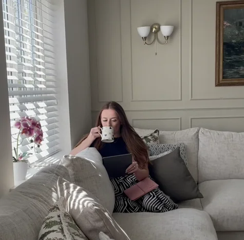 Mia Siddique sitting in her sofa drinking a cup of tea while reading on her reMarkable Paper Pure tablet.