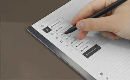 A hand selects the Marker from a tool menu on the reMarkable paper tablet.