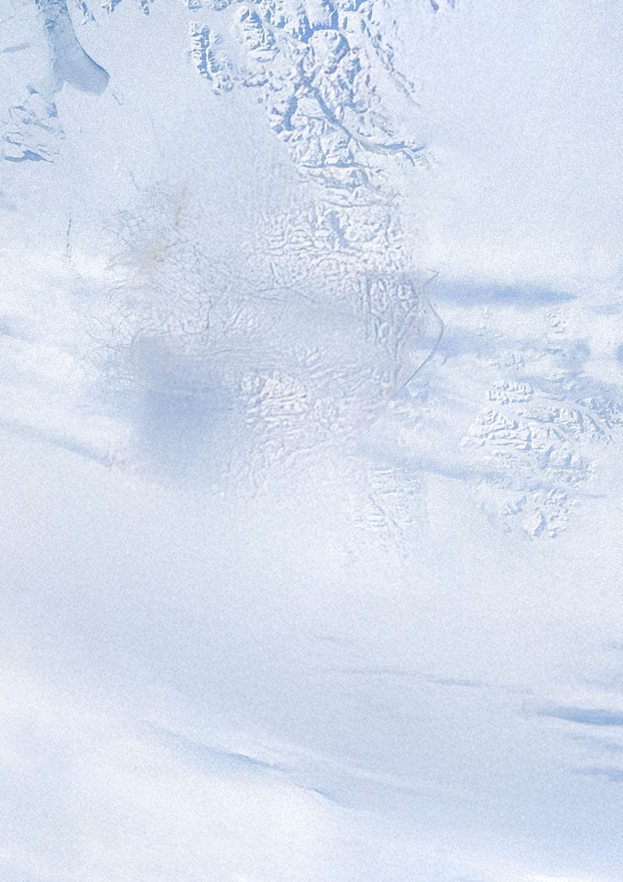 A polar region of the earth as seen from space, with snowy mountains and cloud cover.