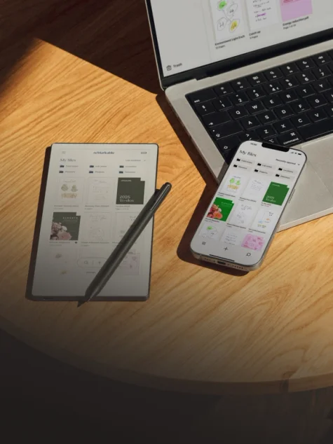 Paper tablet and a phone lying on a desk beside a computer.