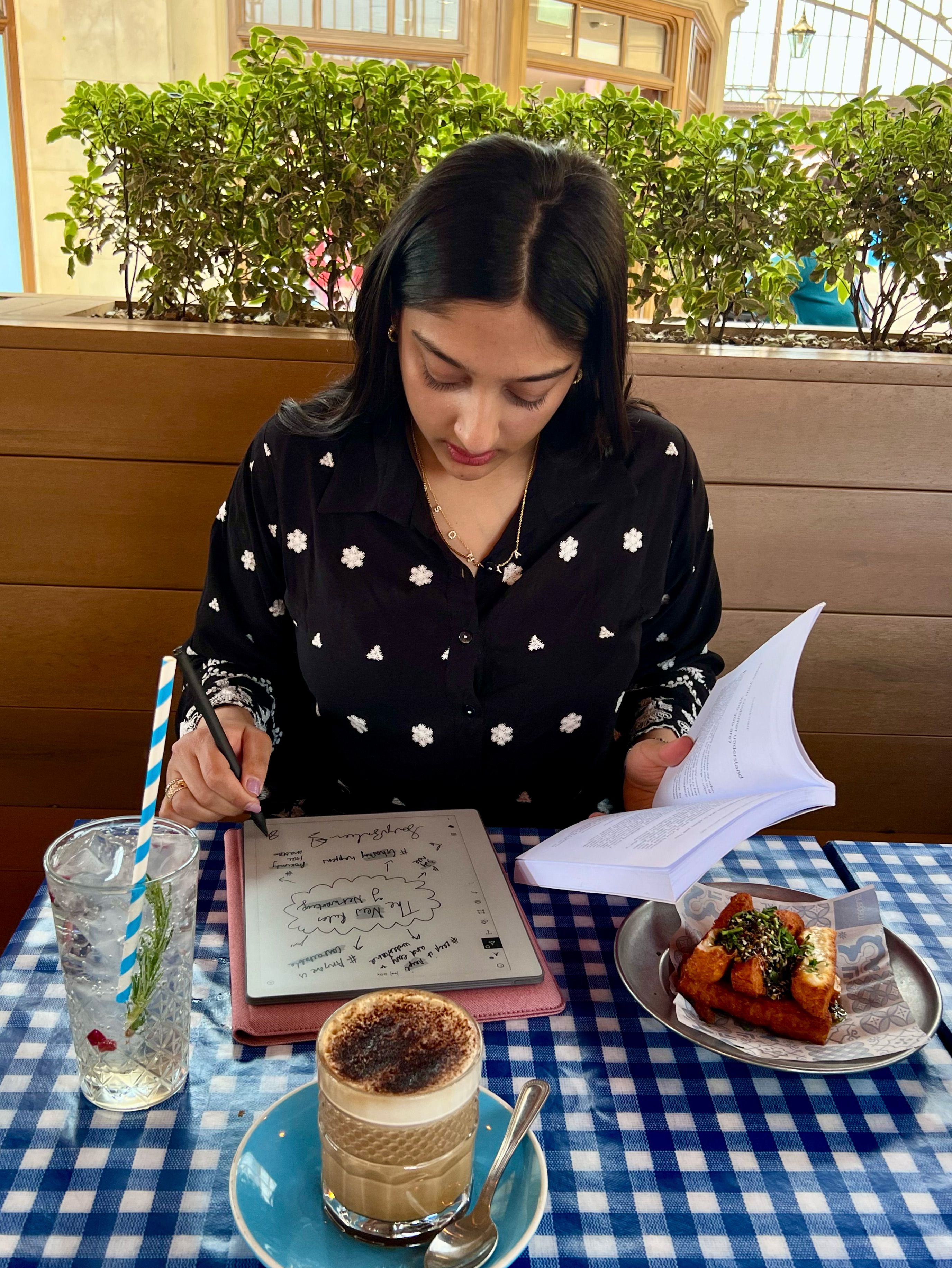 Sonya Barlow sitting outside in a café writing on her reMarkable Paper Pure tablet.