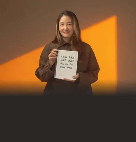 A woman holds a reMarkable paper tablet with the text "I will make sure we're all on the same page".