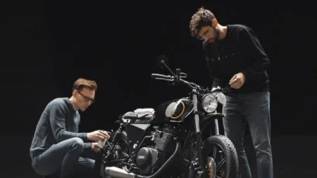 A motorcycle being inspected by two men wearing glasses.