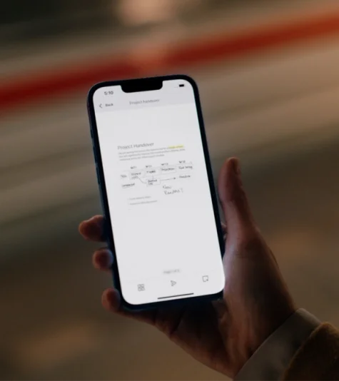 A hand holds a smartphone showing handwritten notes and sketches within the reMarkable mobile app.