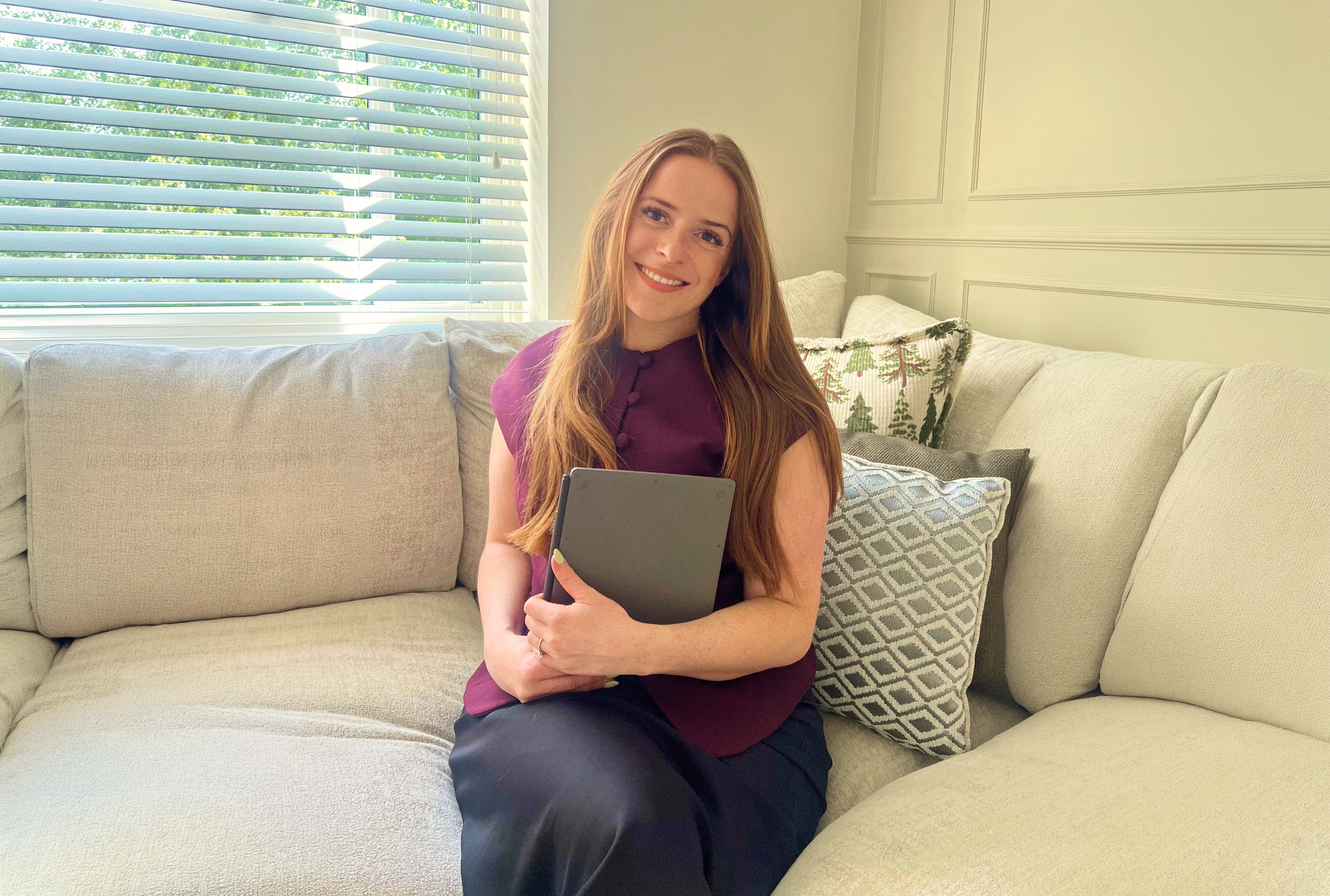 Mia Siddique sitting in her couch holding her reMarkable Paper Pure.
