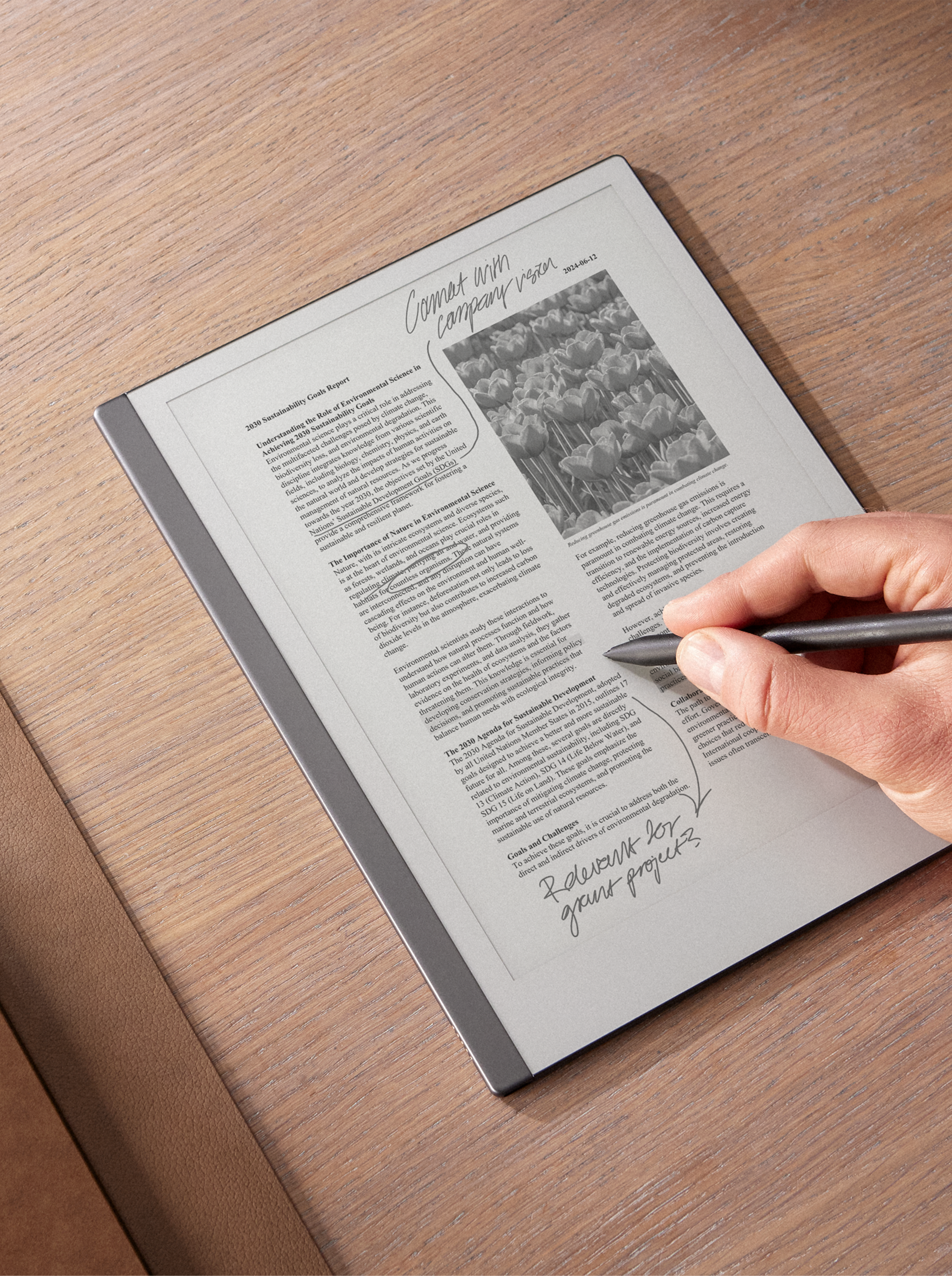 Person writing with Marker Plus on a reMarkable 2 laying on a wood table