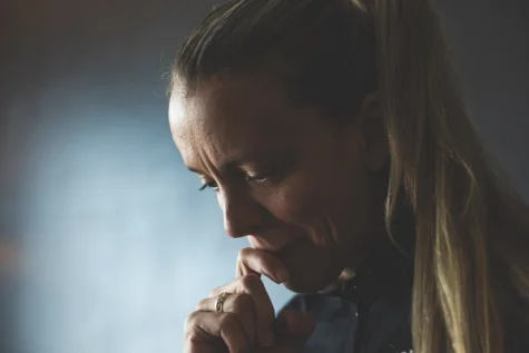 A person thoughtfully looking down with their hand on their chin.