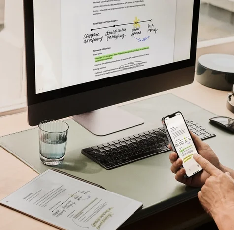 Person reviewing notes on a reMarkable paper tablet while also viewing them on a phone and computer.