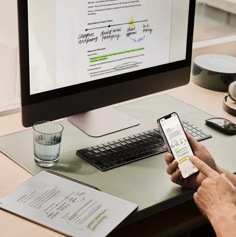 Person reviewing notes on a reMarkable paper tablet while also viewing them on a phone and computer.
