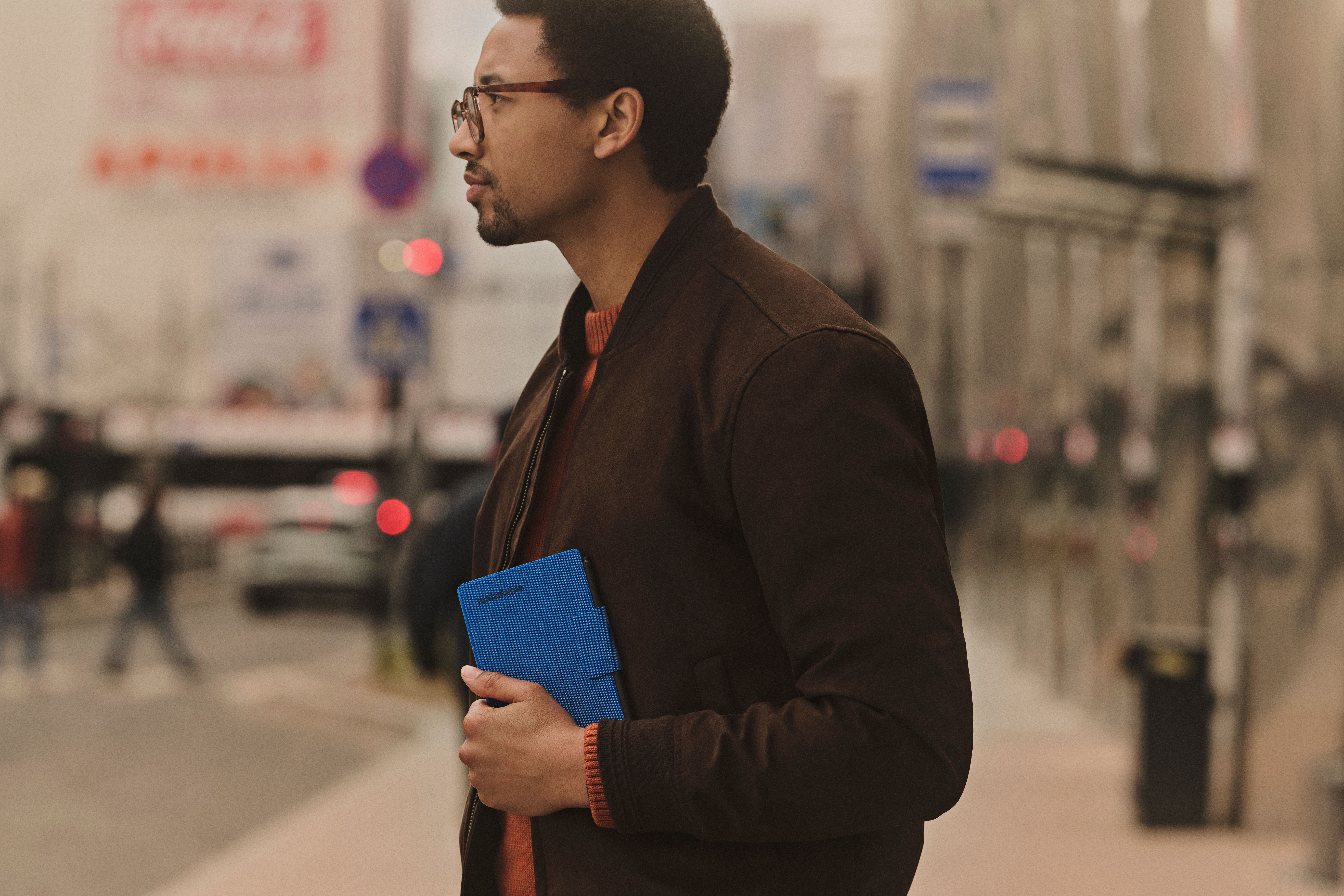 A man on the street carrying the reMarkable Paper Pro Move in a Cobalt Mosaic Weave folio