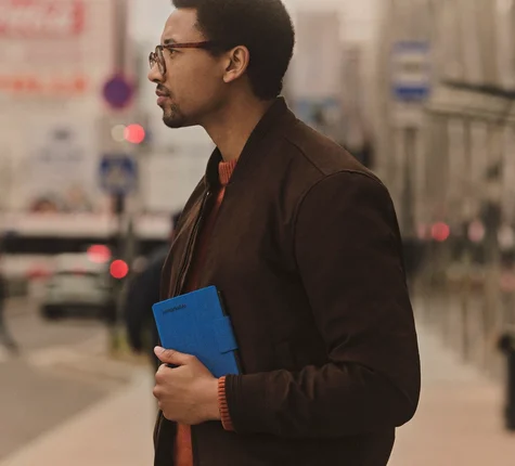 A man holding a reMarkable Paper Pro Move tablet on a city street.