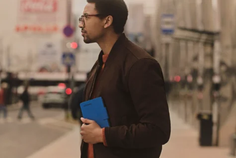 A man holding a reMarkable Paper Pro Move tablet on a city street.