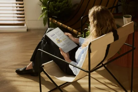 A woman reading in a chair next to a reMarkable paper tablet.
