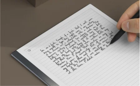 A reMarkable paper tablet with notes and a hand writing with the Marker.