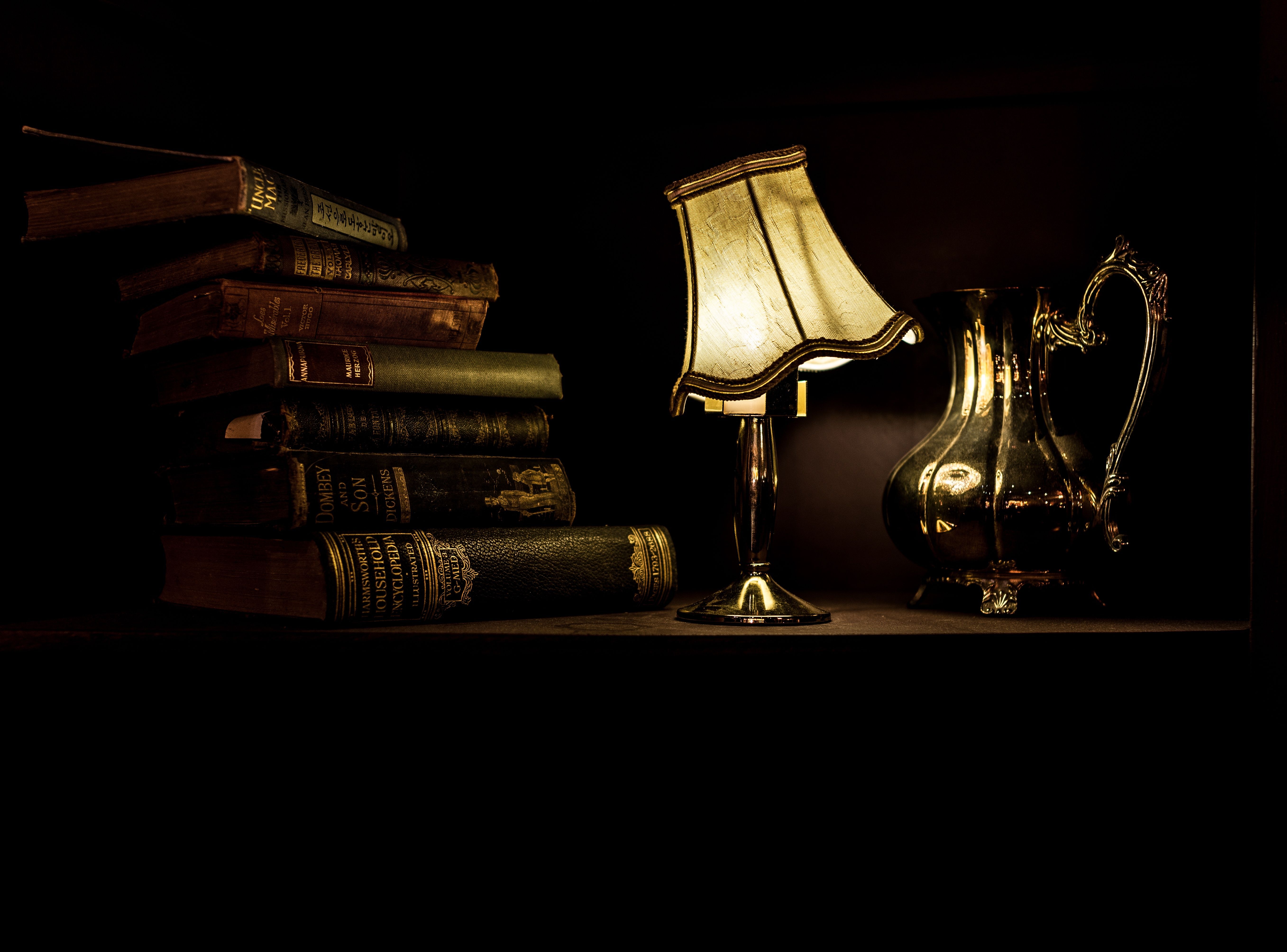 Picture of old books, a lamp, and a silver water pitcher