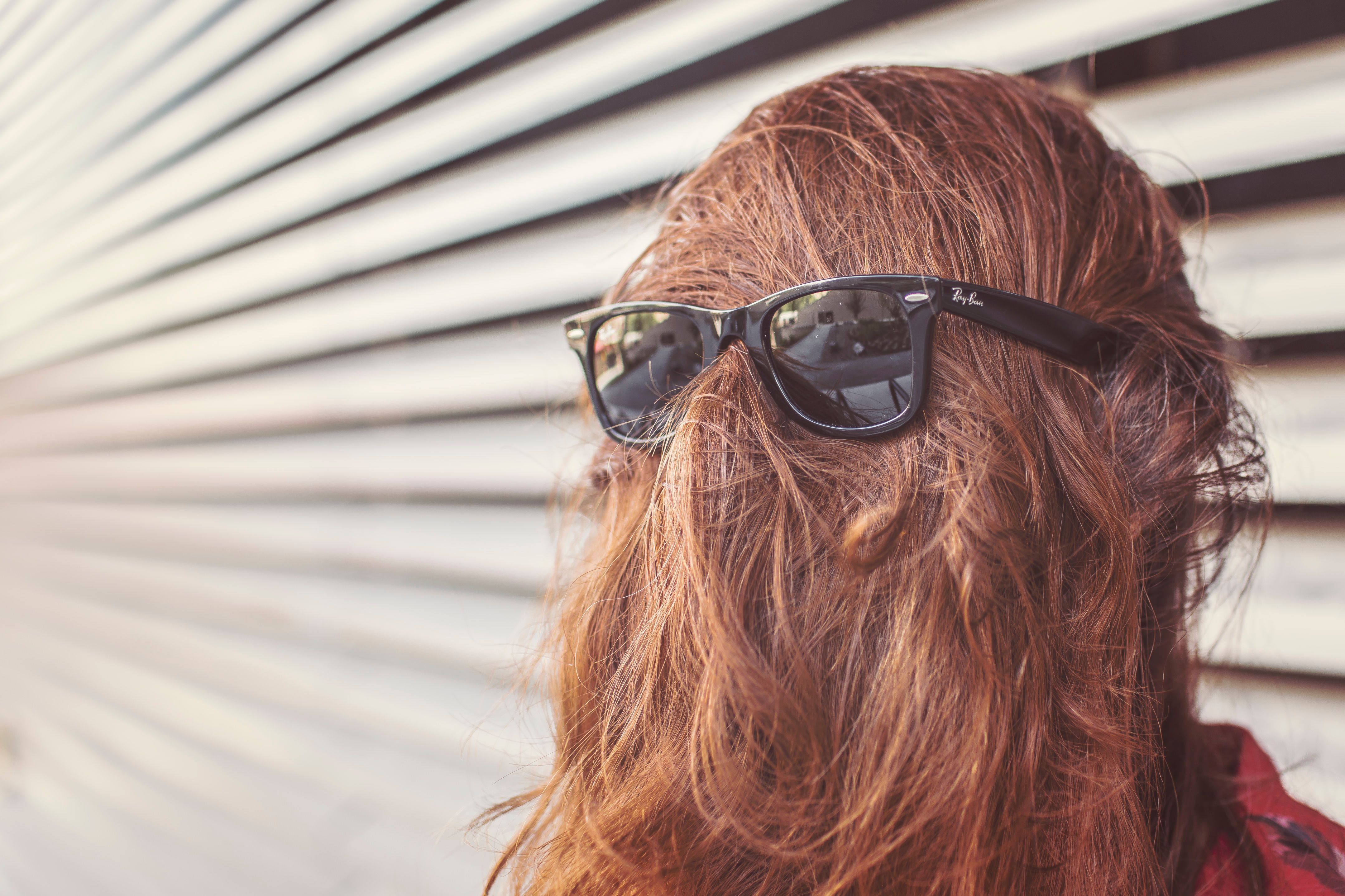 Person with hair covering their face and sunglasses over their hair