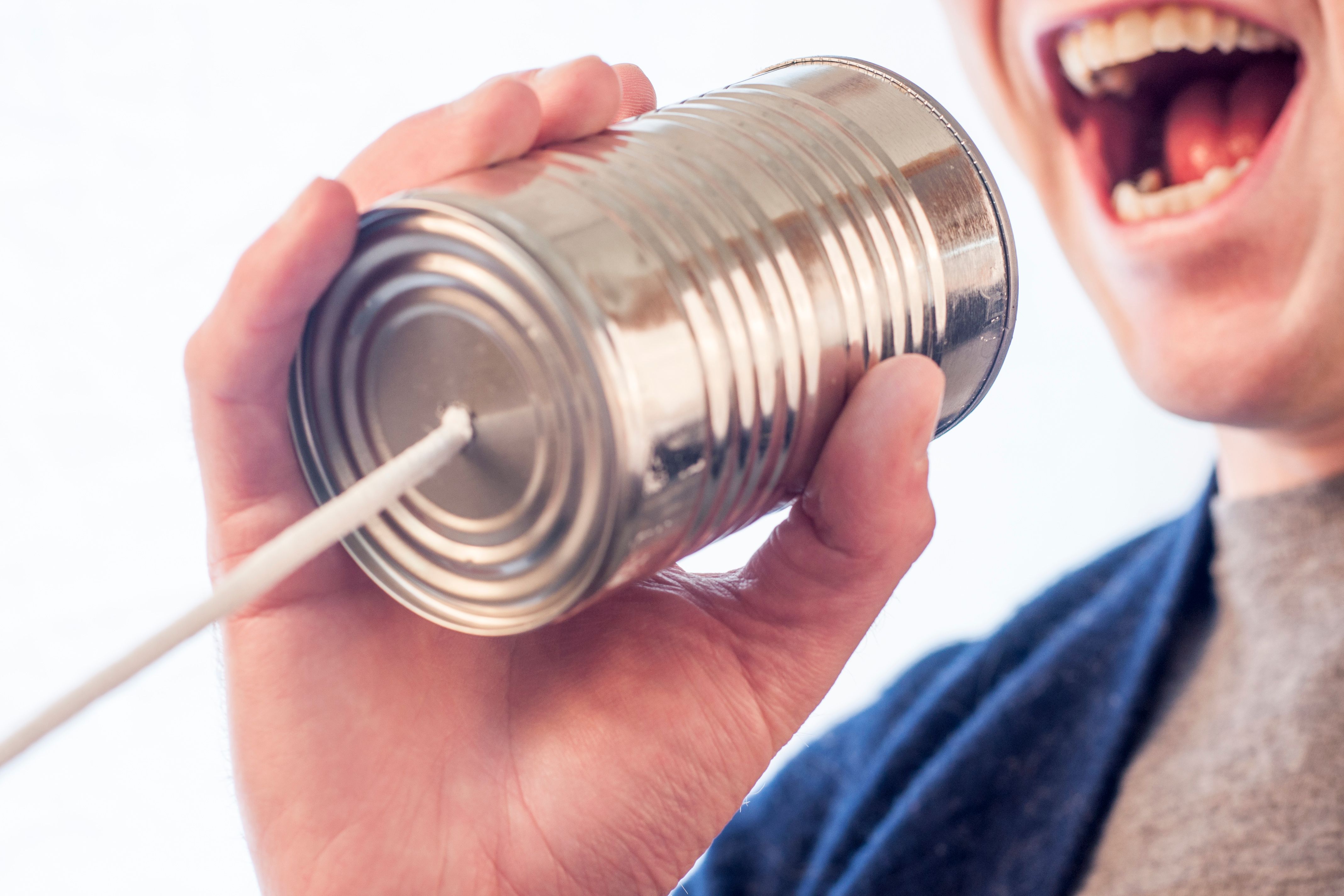 Person shouting in to a can with a string attached to it