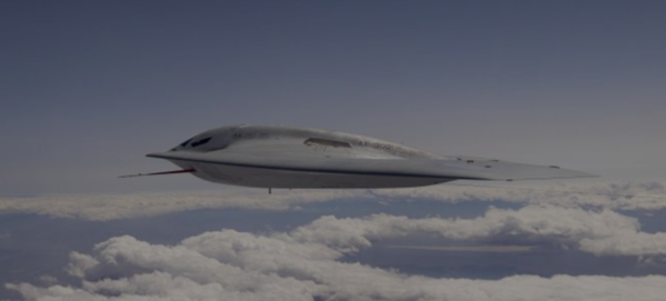 A B-21 Raider flies above the clouds on a clear blue day.