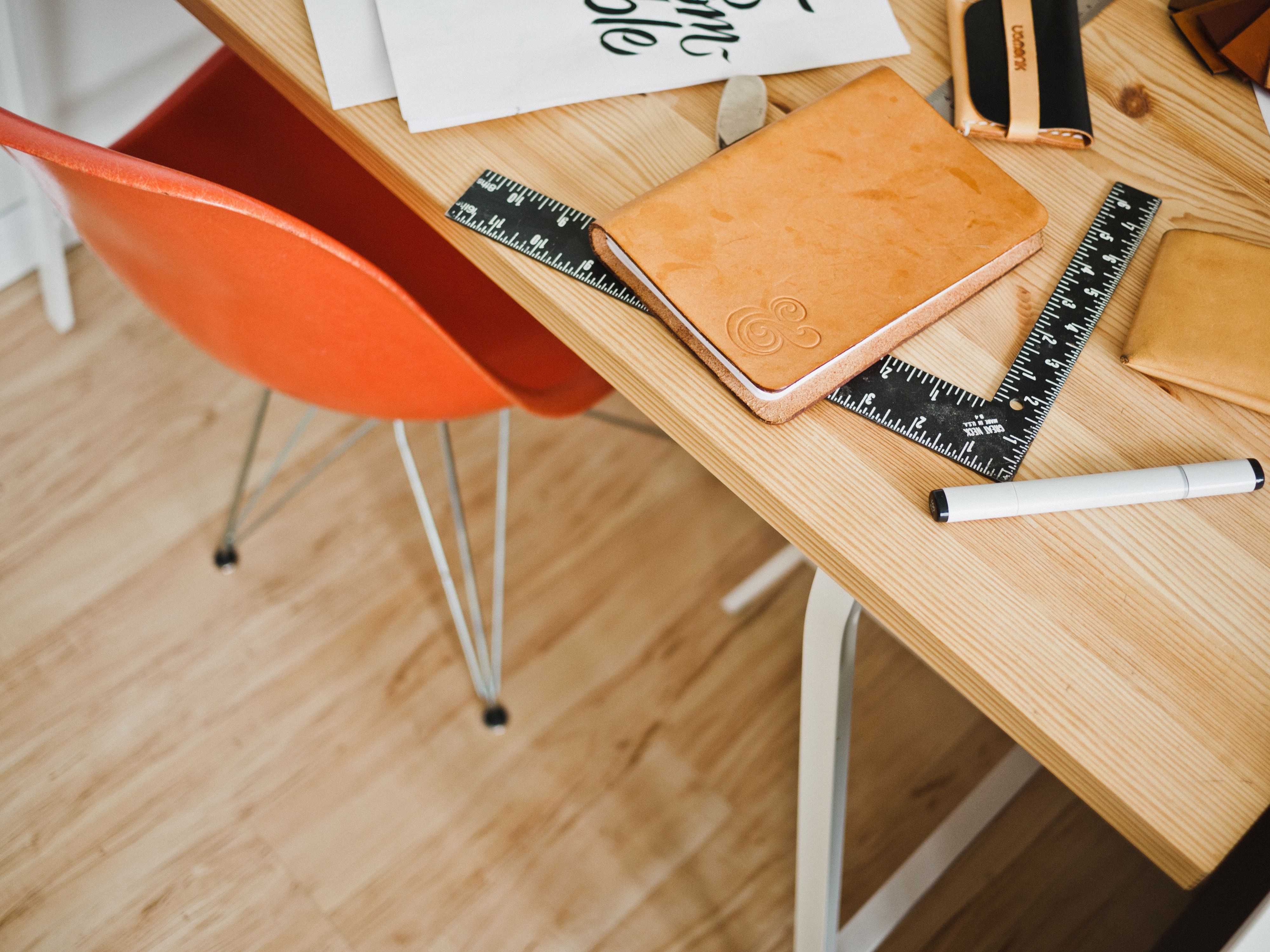 Image of chair and a desk with notebooks, ruler, and marker