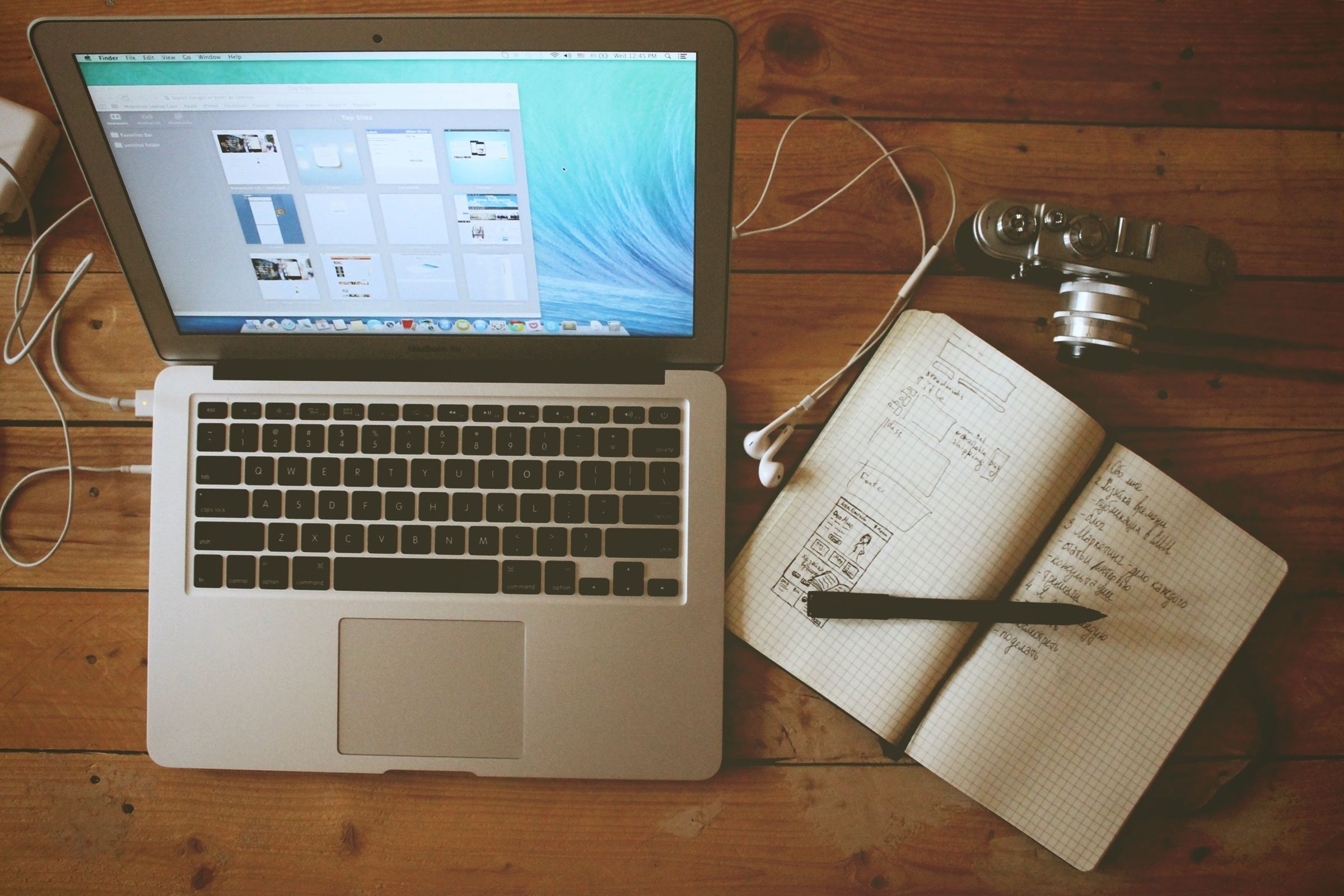 Laptop, open notebook, and headphones sitting on a desk